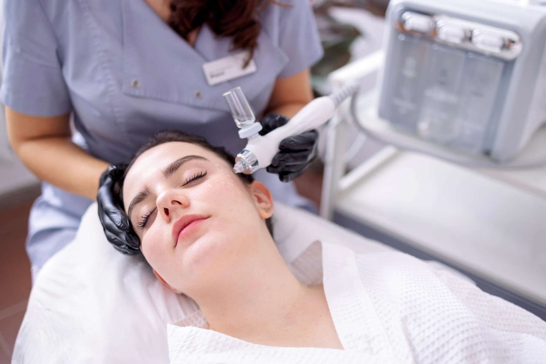 Client receiving a Hydro Boost Facial treatment in a medical spa while a skincare professional uses a hydrating facial device to rejuvenate the skin.